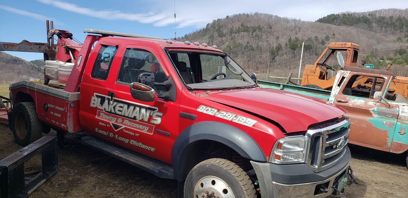 A red tow truck is parked in a dirt field.