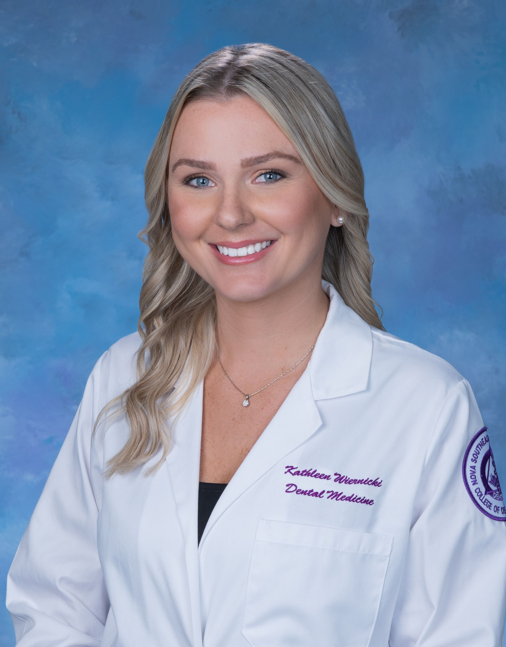 A woman in a white lab coat is smiling for the camera.