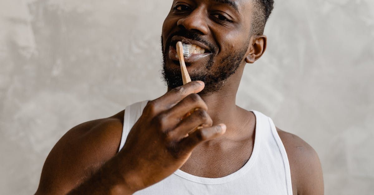 A man is brushing his teeth with a wooden toothbrush.