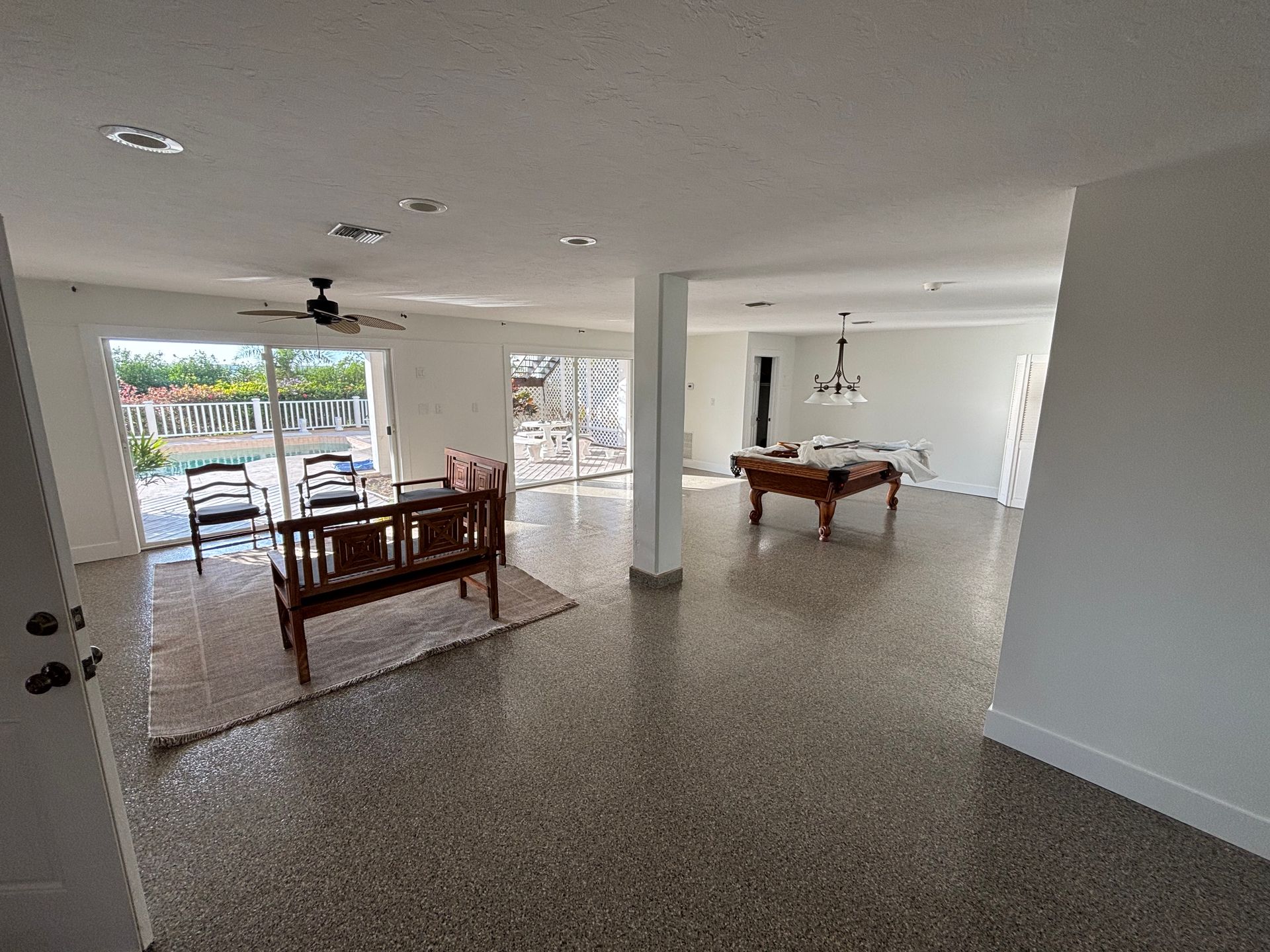 Person wearing gloves sprays blue paint with a spray gun on a gray wall.