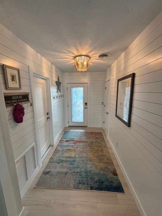 Man wearing overalls, applying plaster to a wall with a trowel.