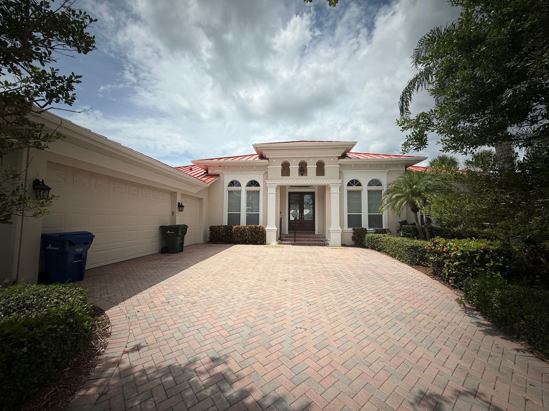 Two men paint a blue wall while precariously perched on a bamboo ladder in an outdoor setting.