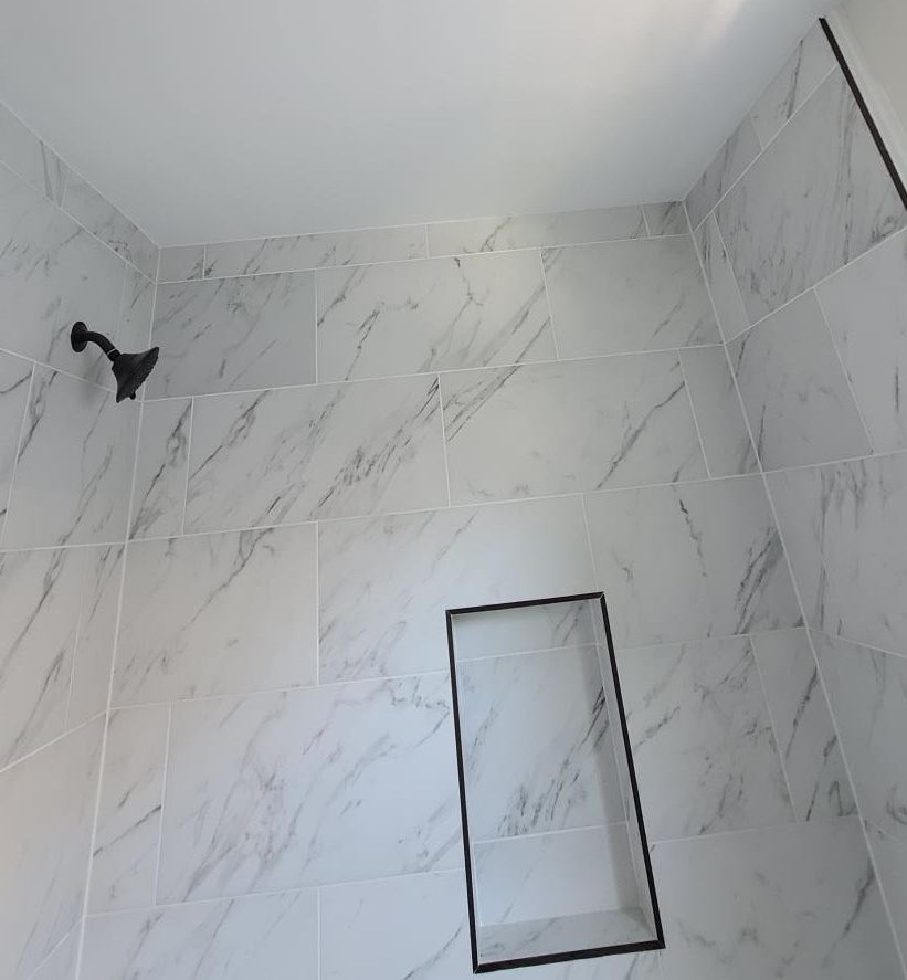 Two men are working on a bathroom and a living room in a house.