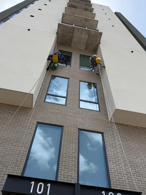 Two men are working on a bathroom and a living room in a house.