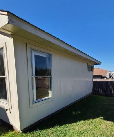 A construction worker is measuring a piece of wood in a kitchen.