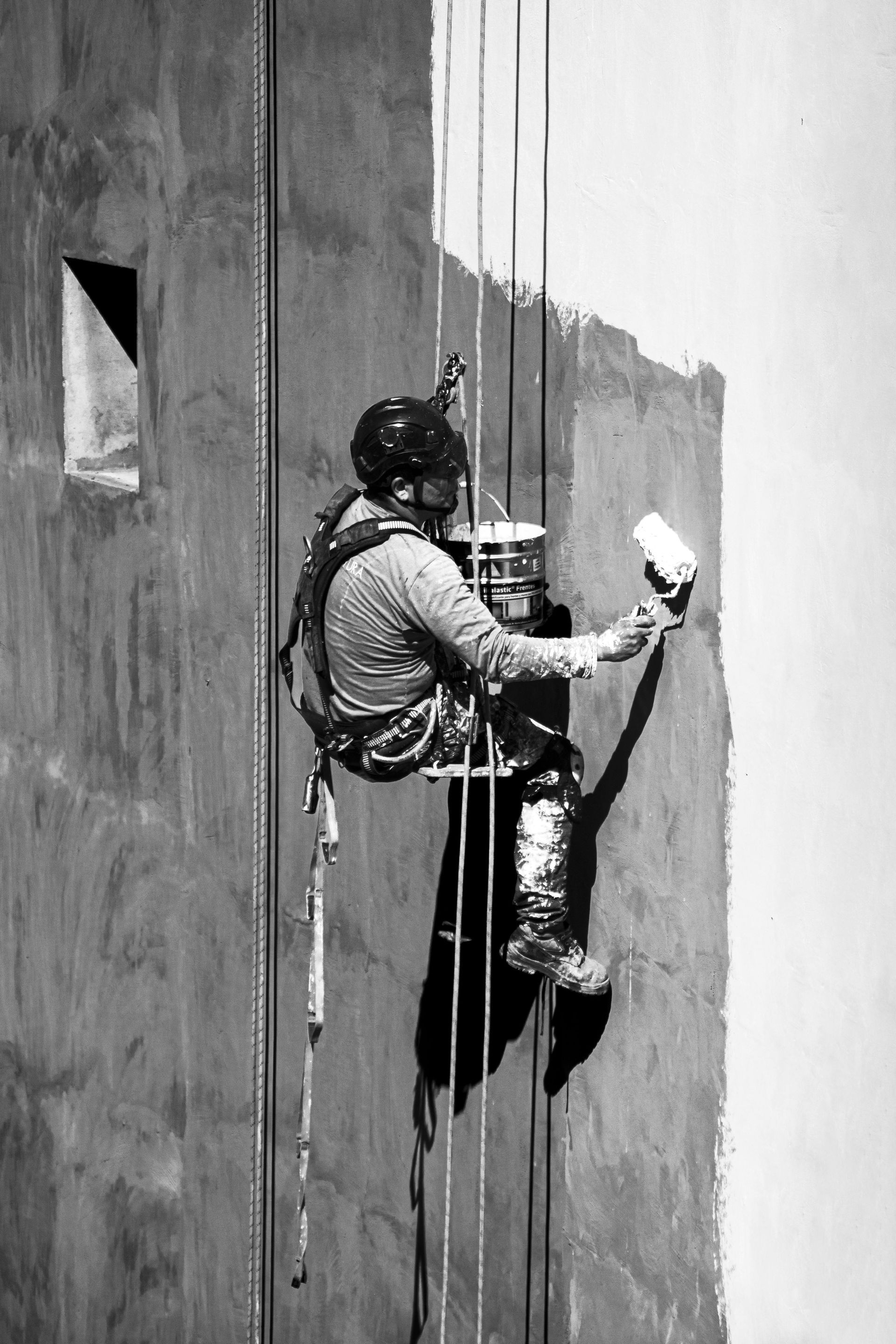 Two men are working on a bathroom and a living room in a house.