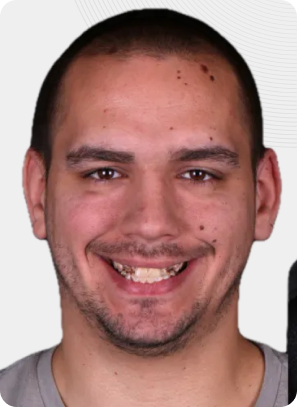 Man with brown eyes smiling, wearing braces. Light skin, short dark hair.