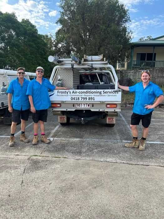 Four People in Blue Shirts Stand Next to a White Truck With — Frostys Air-Conditioning Services in Cannonvale, QLD