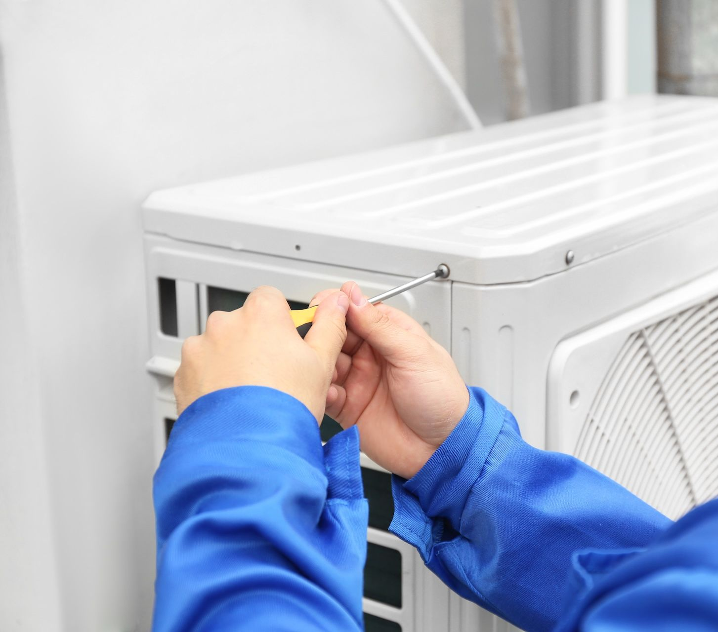Person Servicing Wall-Mounted Air Conditioner Indoors — Frostys Air-Conditioning Services in Cannonvale, QLD