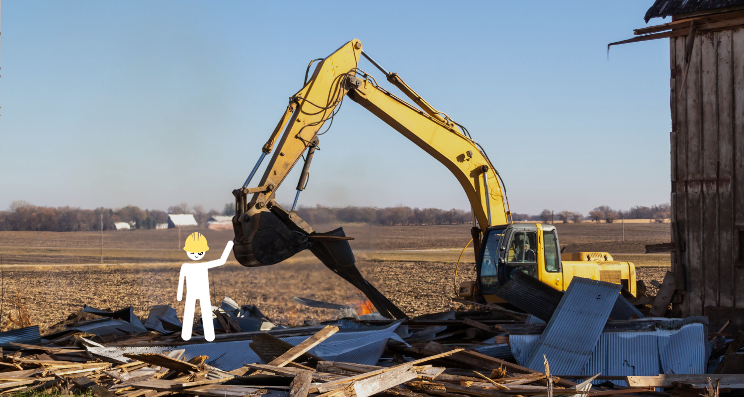 Excavator demolishing an old barn with a white stick figure in a hard hat standing adjacent