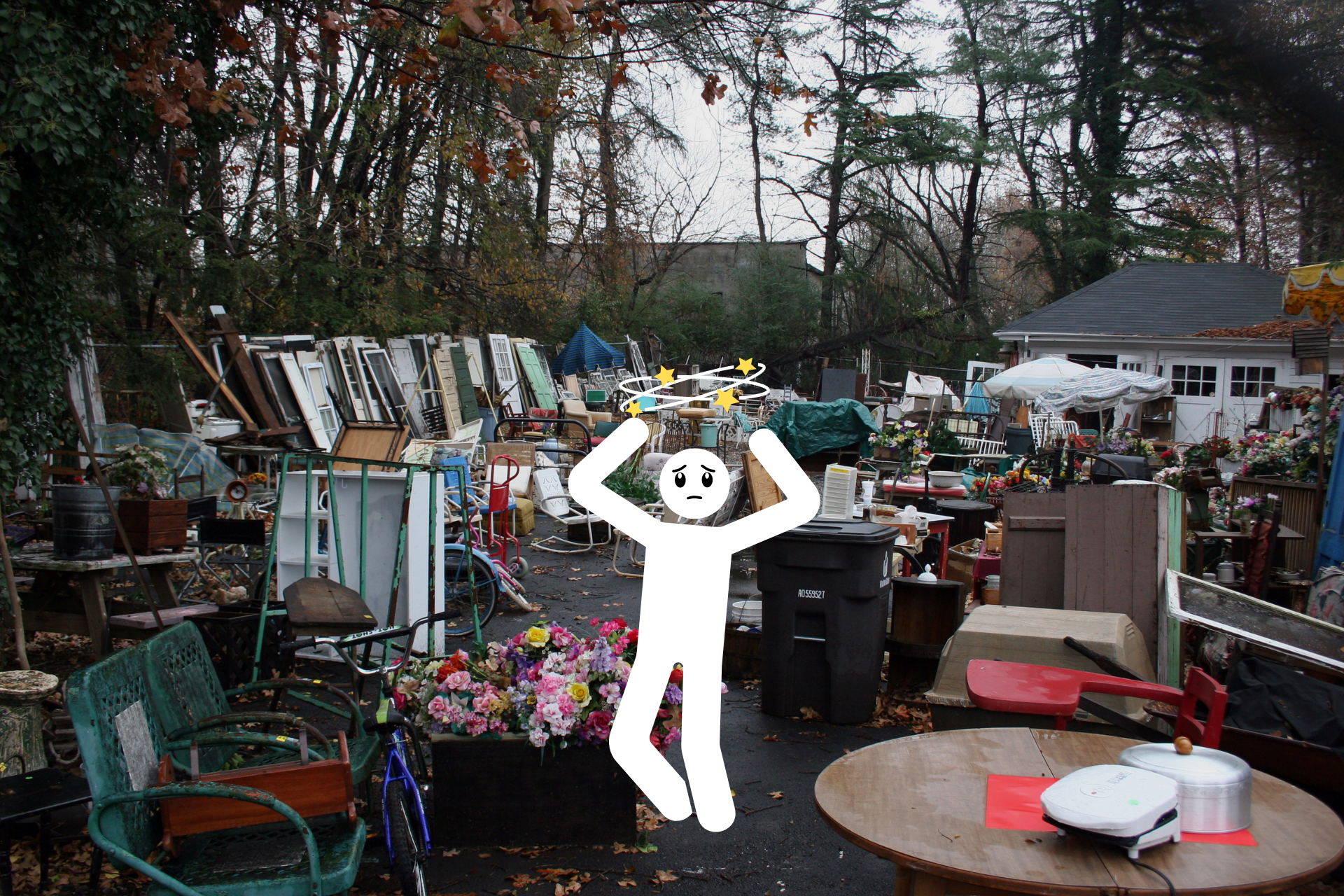 Backyard cluttered with a diverse array of items like doors, pots, plants, trashcans, and dressers,