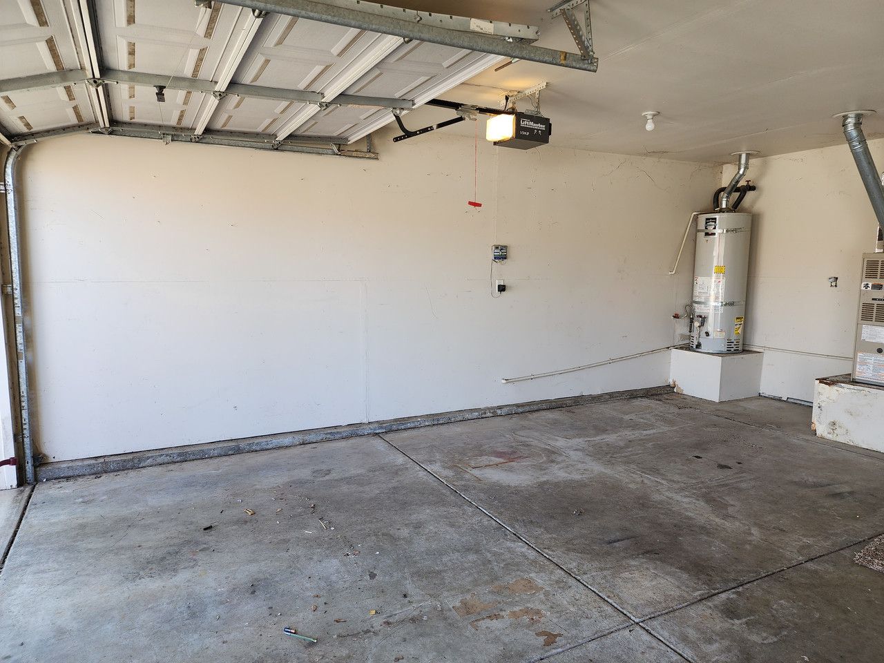Empty garage with clean, uncluttered space, and a lone water heater visible in the background, symbolizing a well-maintained and organized area.