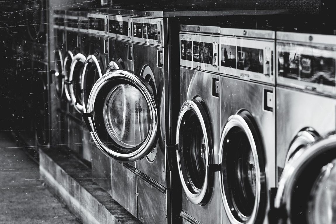 black and white photo of a laundry mat filled with old washing machines