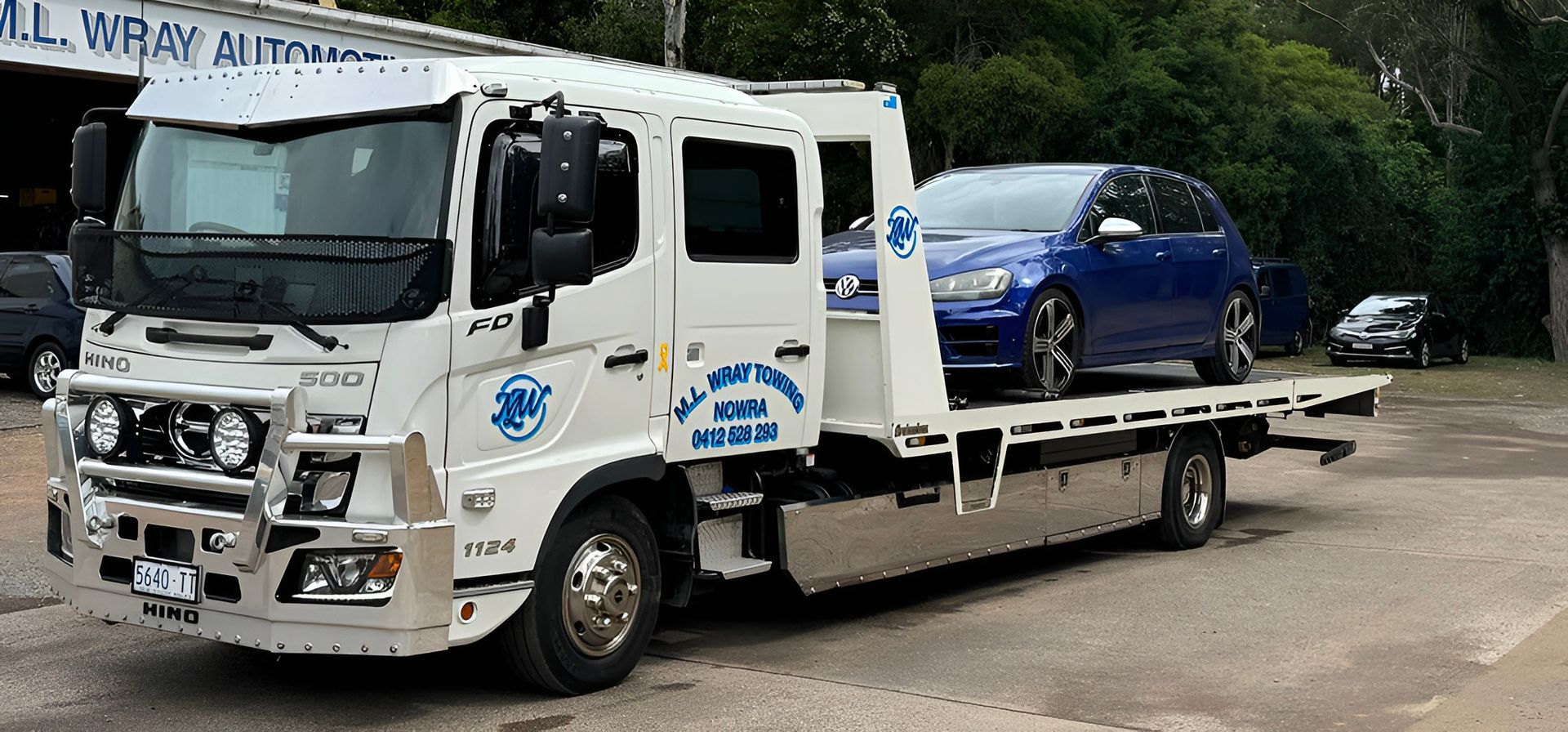 A White Tow Truck Carrying a Blue Car on Its Flatbed — M.L. Wray Towing & Automotive Repairs in Berry, NSW