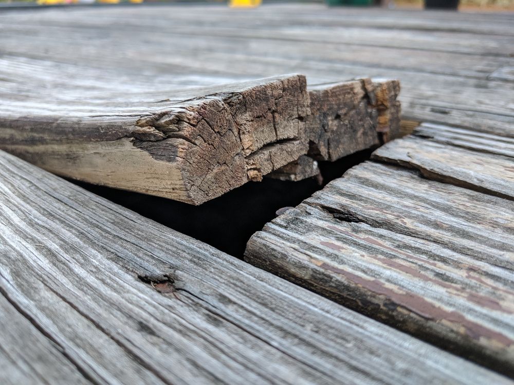 A piece of wood is missing from a wooden deck.