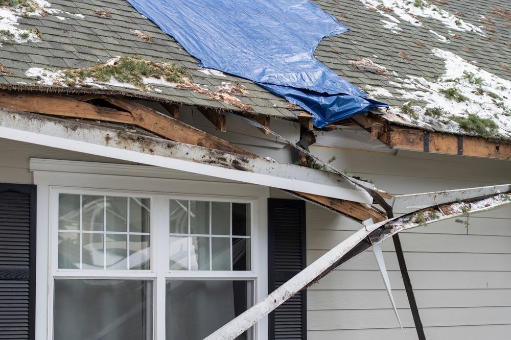 A blue tarp is covering the roof of a house.