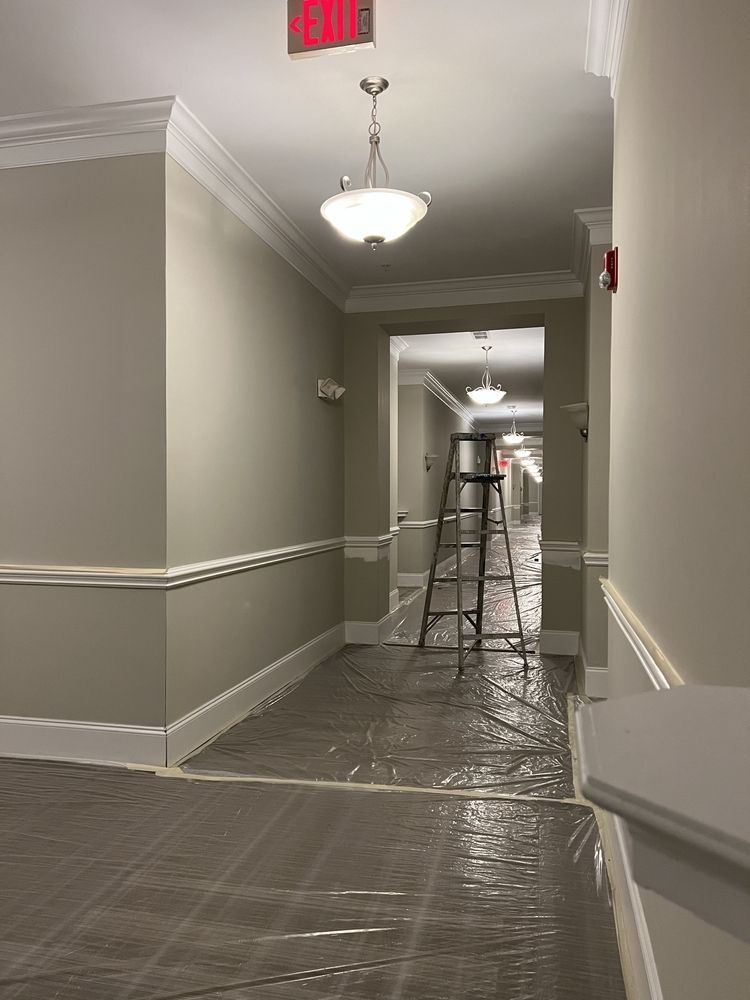 A hallway with a ladder and a red exit sign