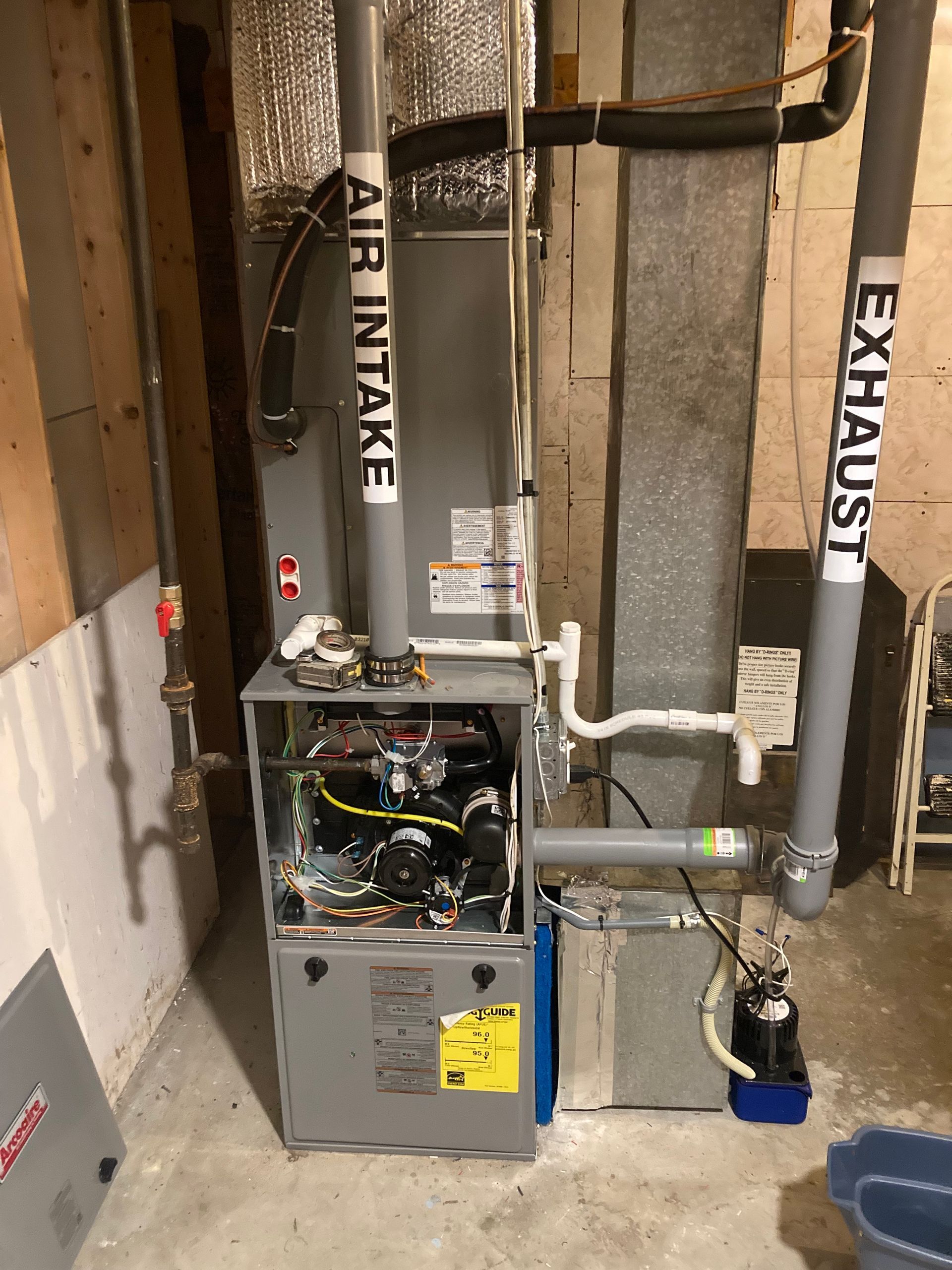 Furnace system in a basement with intake and exhaust pipes labeled.