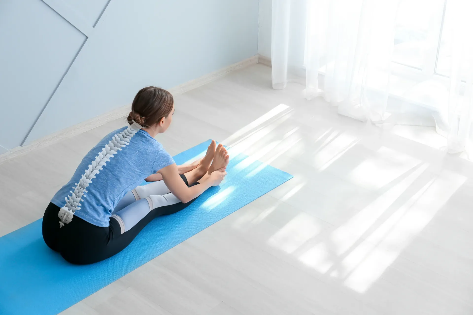 Woman Sitting on Yoga Mat, Stretching Towards Feet — Spinal Decompression Sunshine Coast In Mooloolaba, QLD