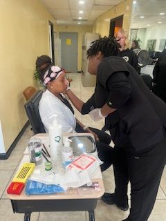 A woman is getting her makeup done by a woman in a salon.
