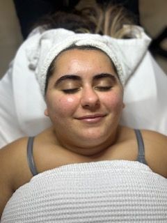 A woman is laying on a bed with a towel wrapped around her head.