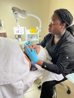 A woman is cleaning a person 's face in a beauty salon.