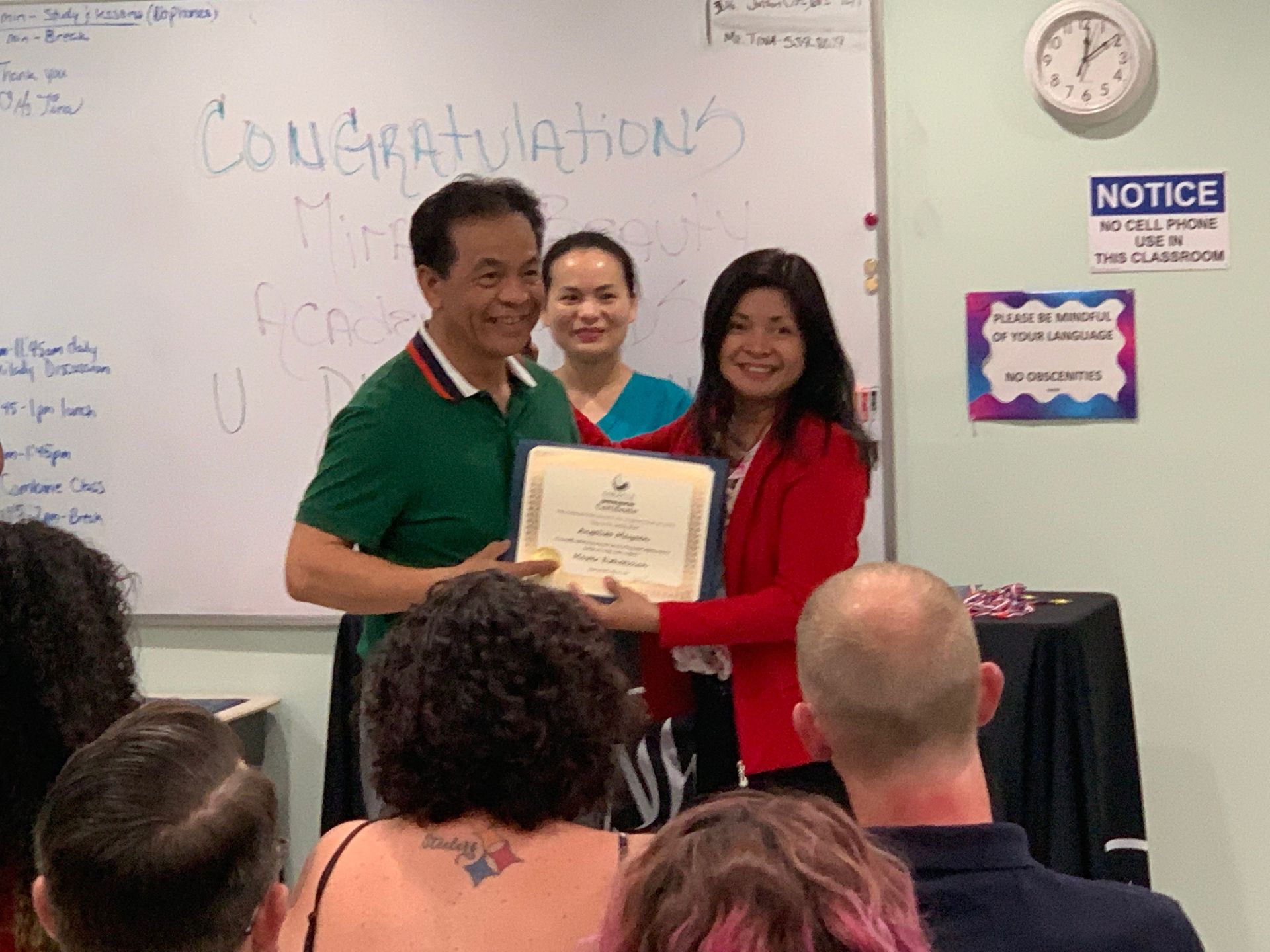 A group of people are standing in front of a whiteboard holding a certificate.