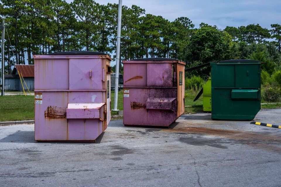 Three large dumpsters on pavement