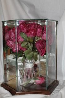 Bouquet of pink roses in a glass display case on a wooden base