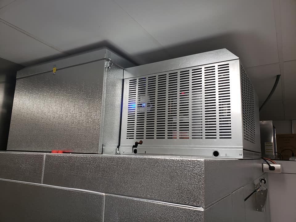 A metal box is sitting on top of a brick wall.