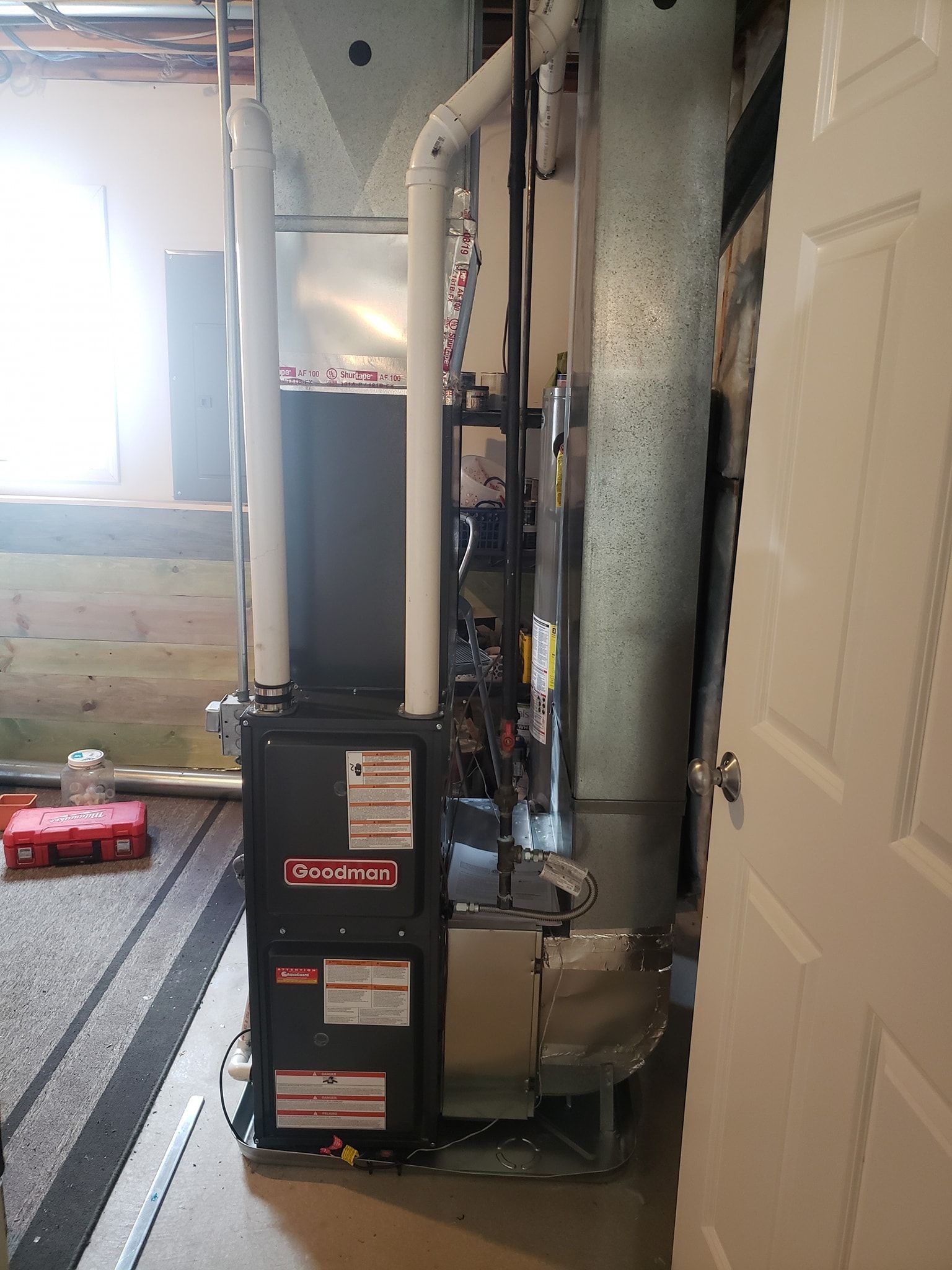 An air conditioner is sitting in a room next to a door.
