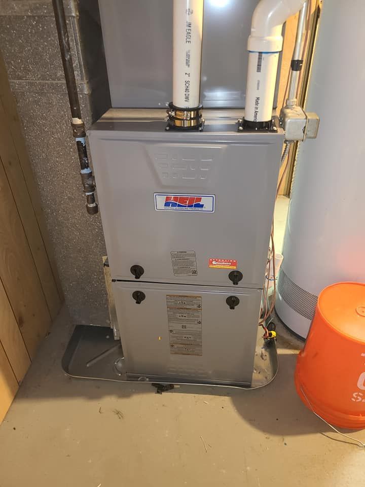 A furnace is sitting in a basement next to a water heater.