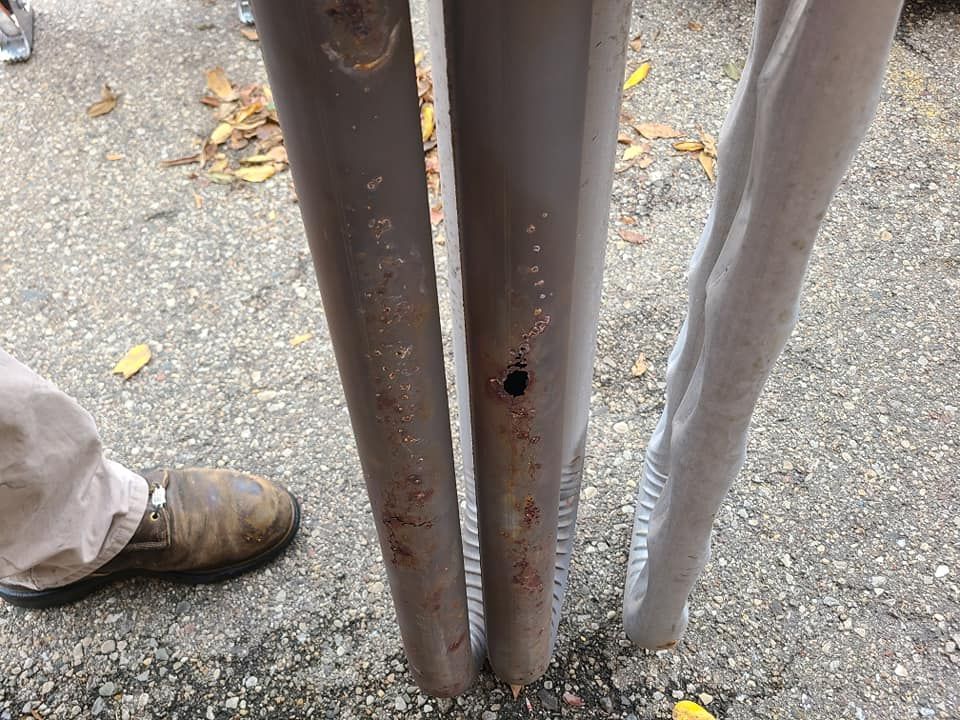 A person is standing next to a metal pole with a hole in it.
