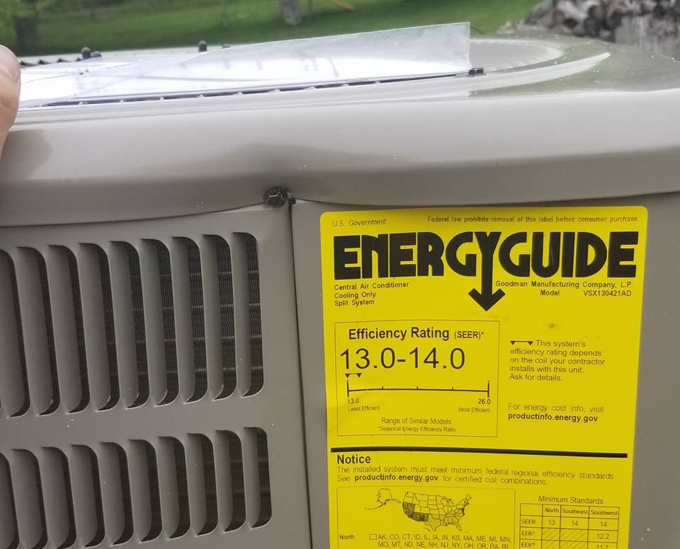 A person is holding an air conditioner with an energy guide label on it.