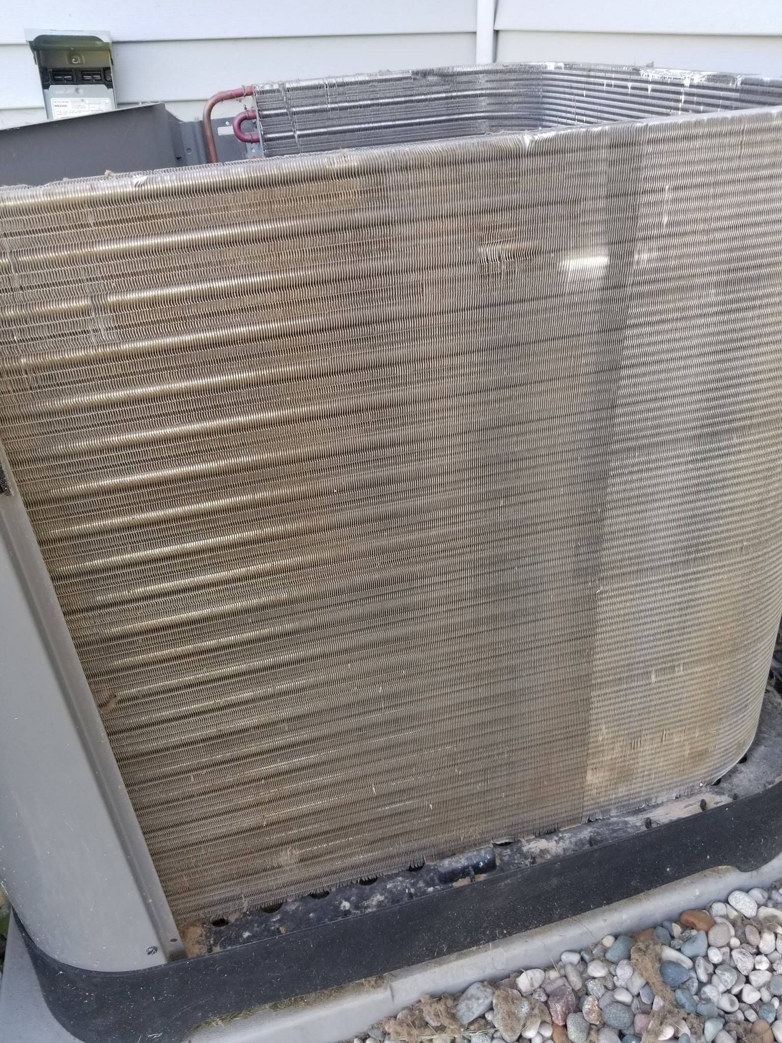 A close up of a dirty air conditioner outside of a house.