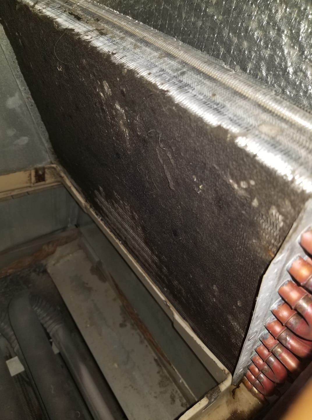 A close up of a dirty air conditioner coil in a room.