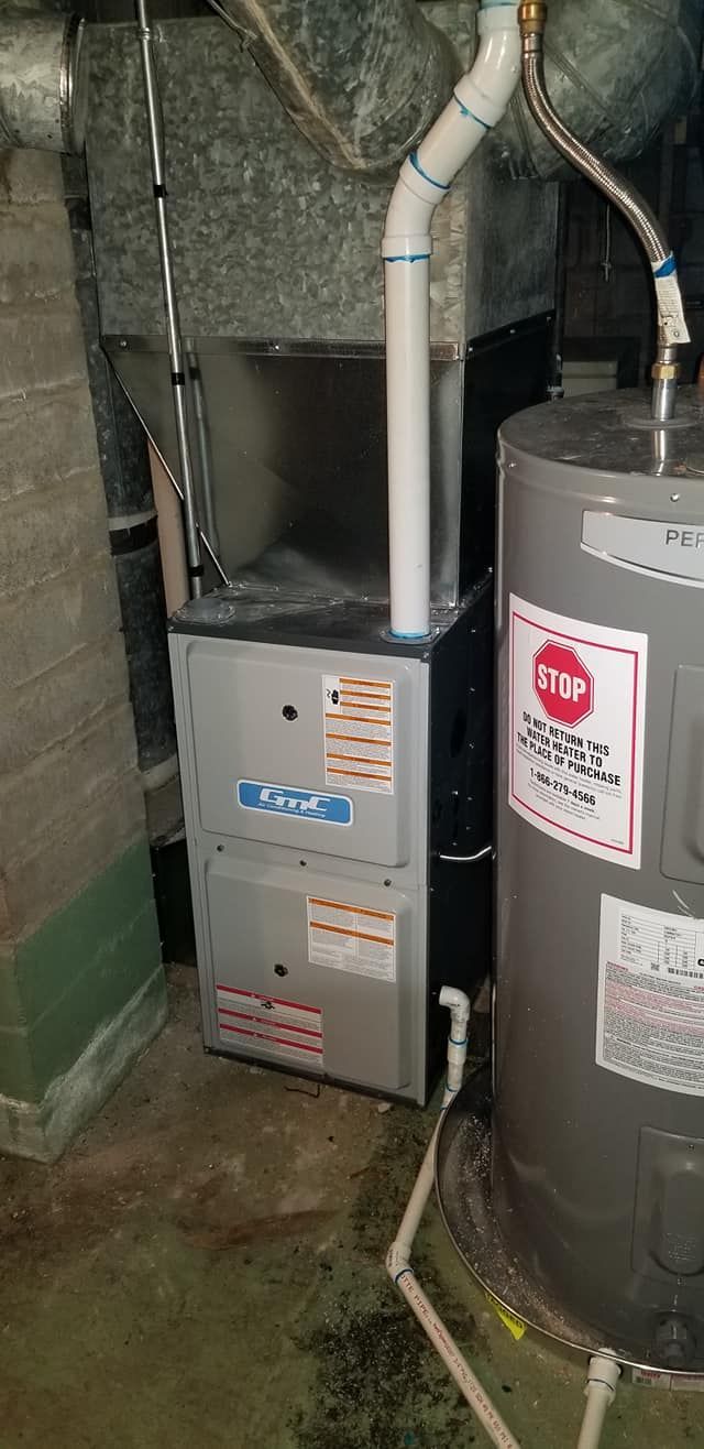 A water heater is sitting next to a furnace in a basement.