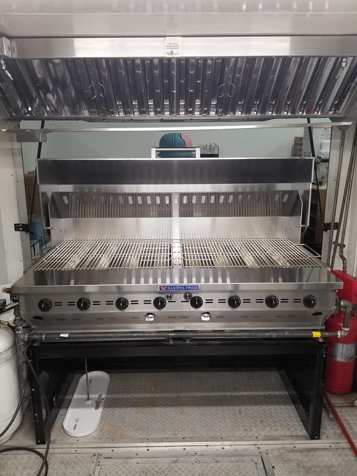 A large stainless steel grill is sitting in a kitchen.