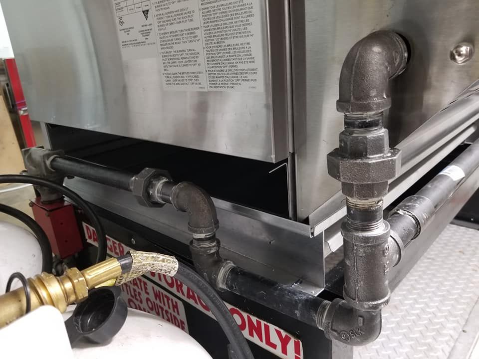 A stainless steel oven with a propane tank attached to it