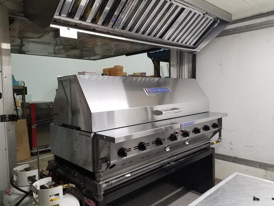 A large stainless steel grill is sitting on top of a table in a kitchen.