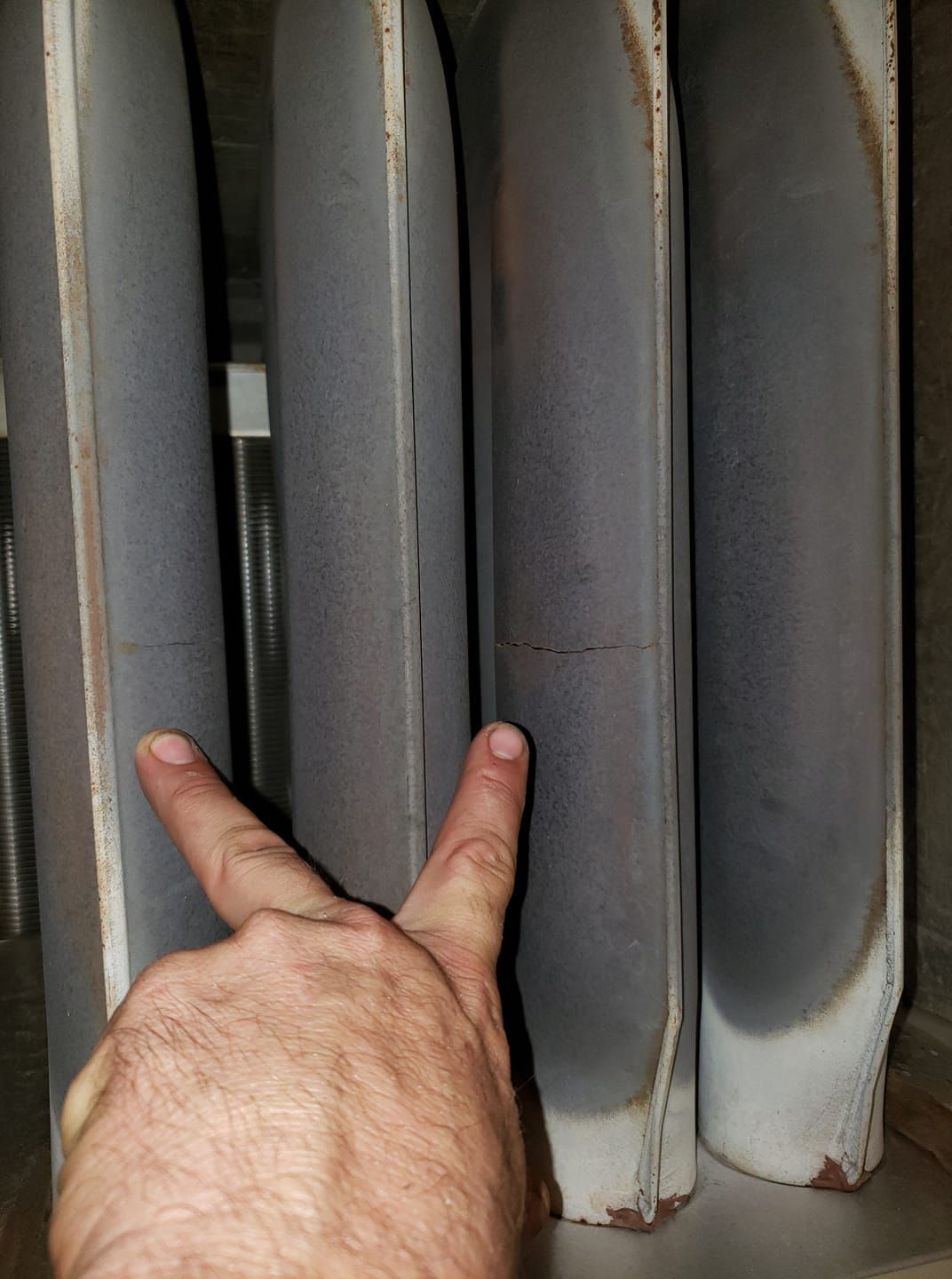 A person is pointing at a radiator with their fingers.