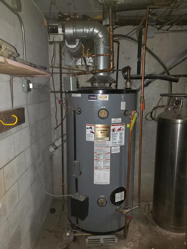 A water heater is sitting in a basement next to a propane tank.