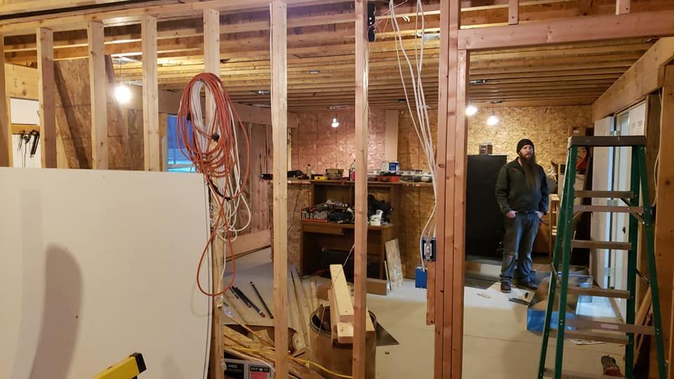 A man is standing in a room that is being remodeled.