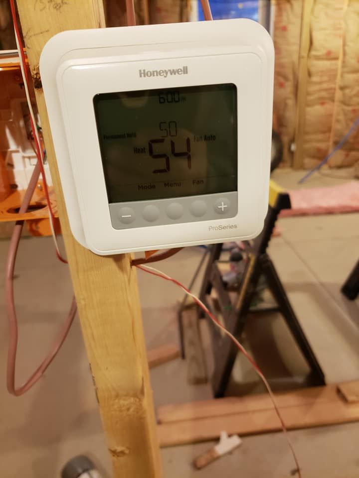 A honeywell thermostat is sitting on a wooden post.