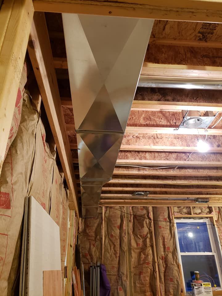 A room with a lot of wooden beams and a metal pipe coming out of the ceiling.