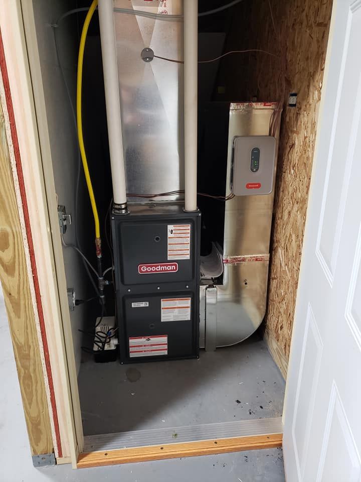 A furnace is sitting in a closet next to a door.