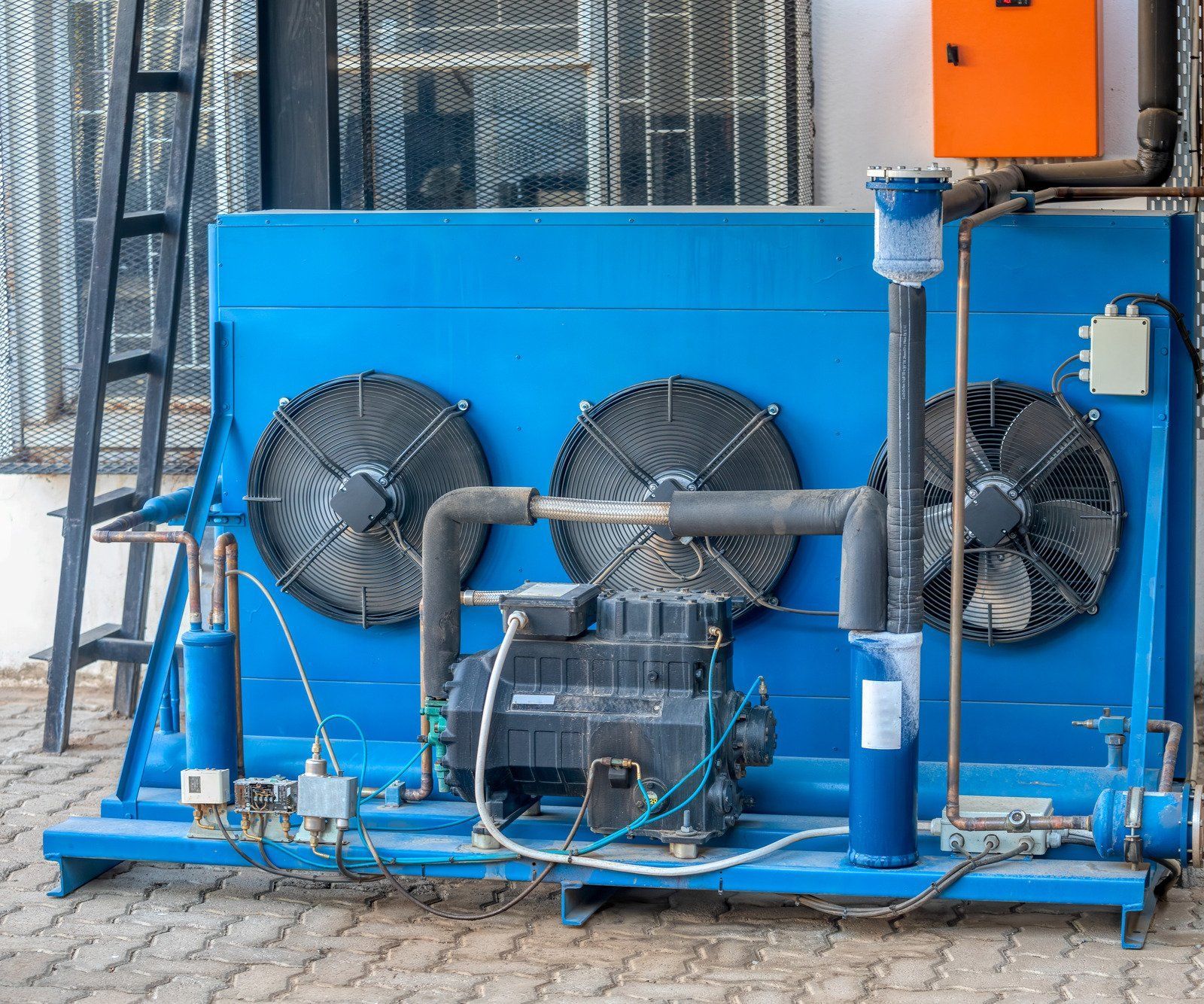 A blue machine with a lot of fans on it is sitting on the ground.