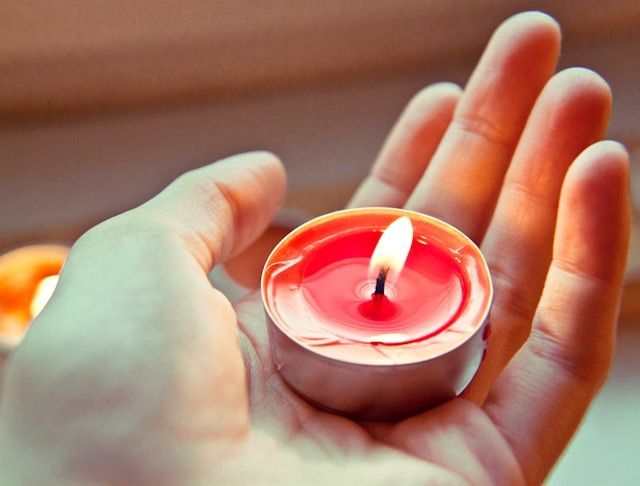 Hand holding lit memorial candle for cremation services in Portland, ME