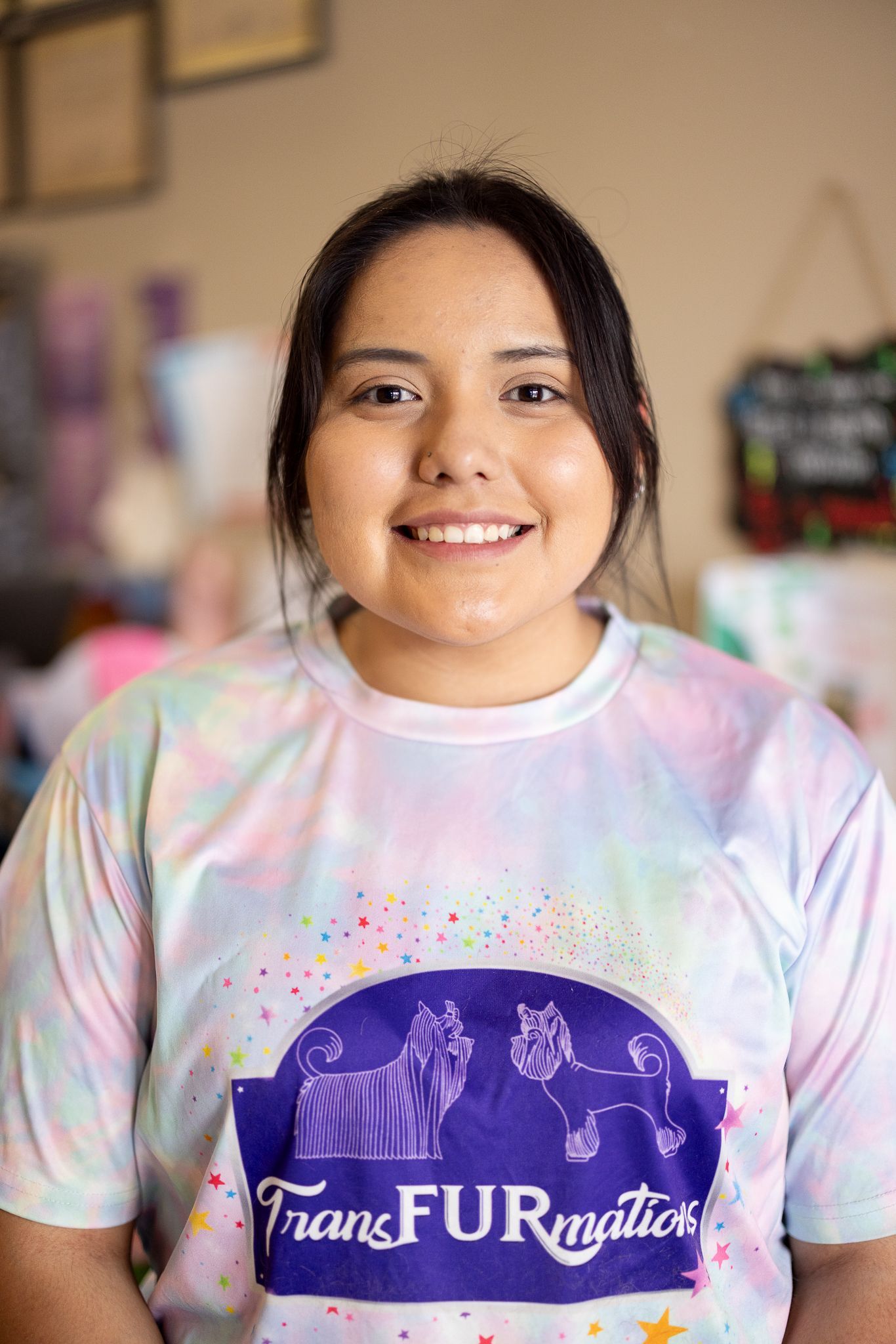 A woman wearing a tie dye shirt is smiling for the camera.
