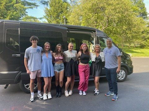A group of people are posing for a picture in front of a van.